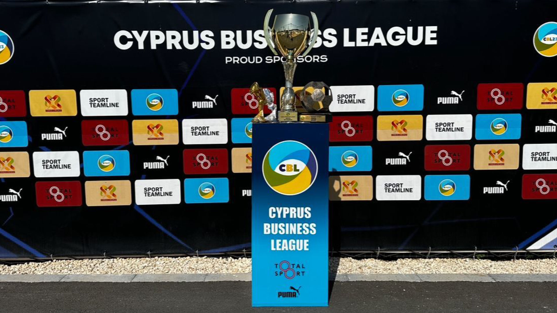 Podium of the Cyprus Business League 2023/24 awards ceremony featuring trophies and a backdrop of sponsor banners.