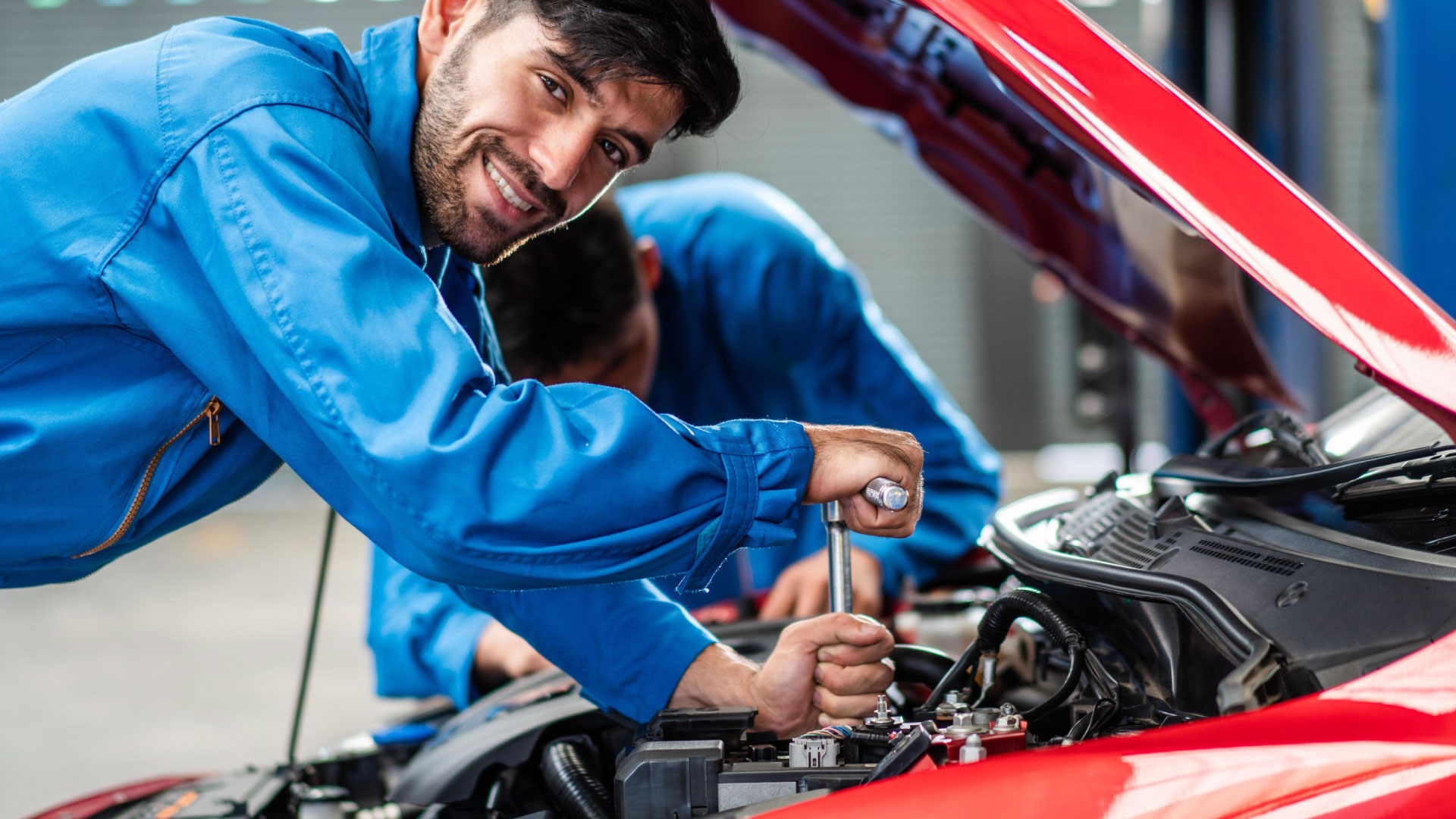 A mechanic repairing a car, emphasizing the importance of investing in essential tools and maintaining a well-organized workspace, as discussed in the guide 'Starting Your Own Auto Shop.’