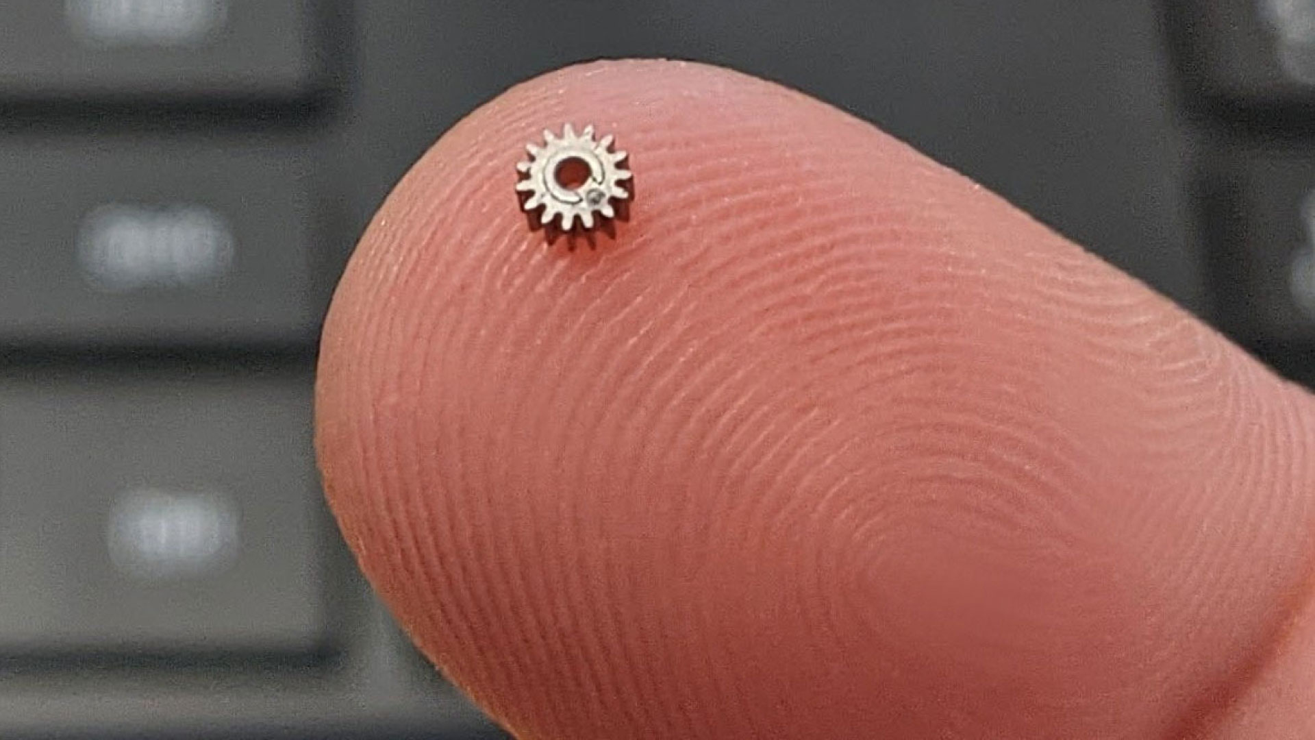 A small gear on the tip of a finger, representing the precision and customization capabilities of medical injection molding in creating intricate medical devices.